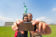 Couple Taking A Selfie With Statue Of Liberty On Background