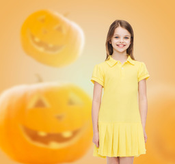 Wall Mural - smiling girl in dress over pumpkins background