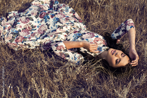 Tapeta ścienna na wymiar beautiful woman in colorful dress lying in field