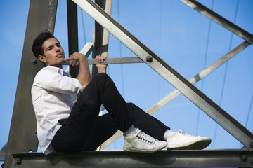 Wall Mural - Handsome young man sitting on metal electricity trellis