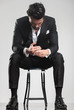 © Viorel Sima - man in tuxedo looking down while sitting on a stool,