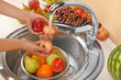 Woman's hands washing peaches and other fruits in colander in