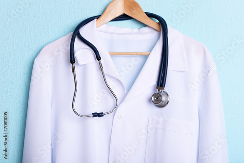 Fotografie, Tablou Doctor coat with stethoscope on hanger on blue background