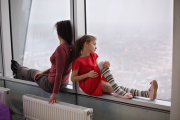 Woman and young girl sitting on the windowsill