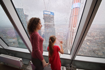 Mother and daughter looking through a large window