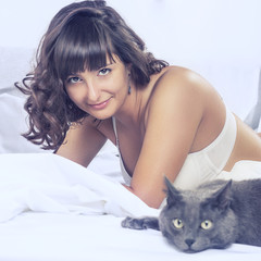 smiling beautiful brunette girl in her bed and cat