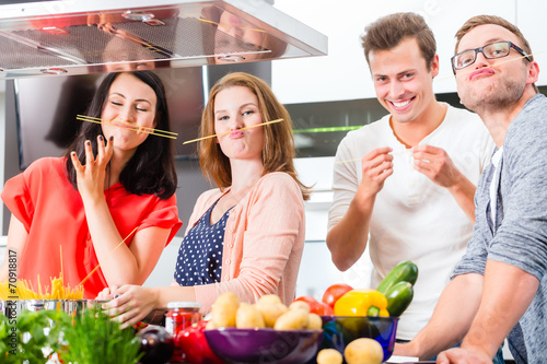 Fotografie, Obraz Freunde kochen Pasta und Fleisch zuhause in Küche