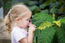 Cute Little Girl Smelling A Flower