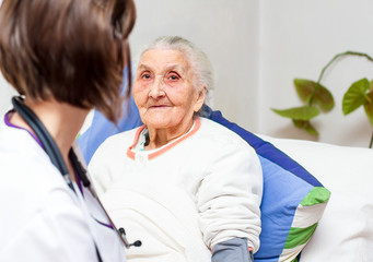 young nurse caregiving an old lady lying in bed