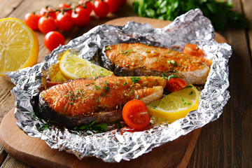 Tasty baked fish in foil on table close-up