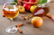 Apple cider in wine glass and bottle, with cinnamon sticks and
