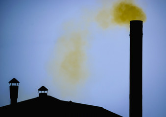 Yellow smoke from Silhouette of factory pipe over dark blue sky