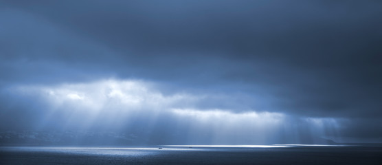 Sunlight goes through blue stormy clouds. Bay of Tangier, Morocc