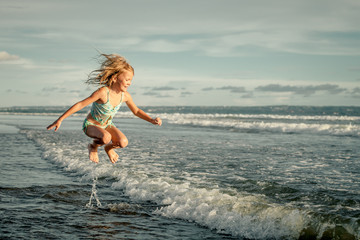 Wall Mural - little girl running on the beach at the day time