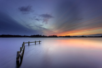 Poster - Winter Sunset over Tranquil Lake with Wooden Mooring Post