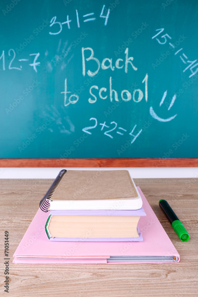 School supplies on table on blackboard background