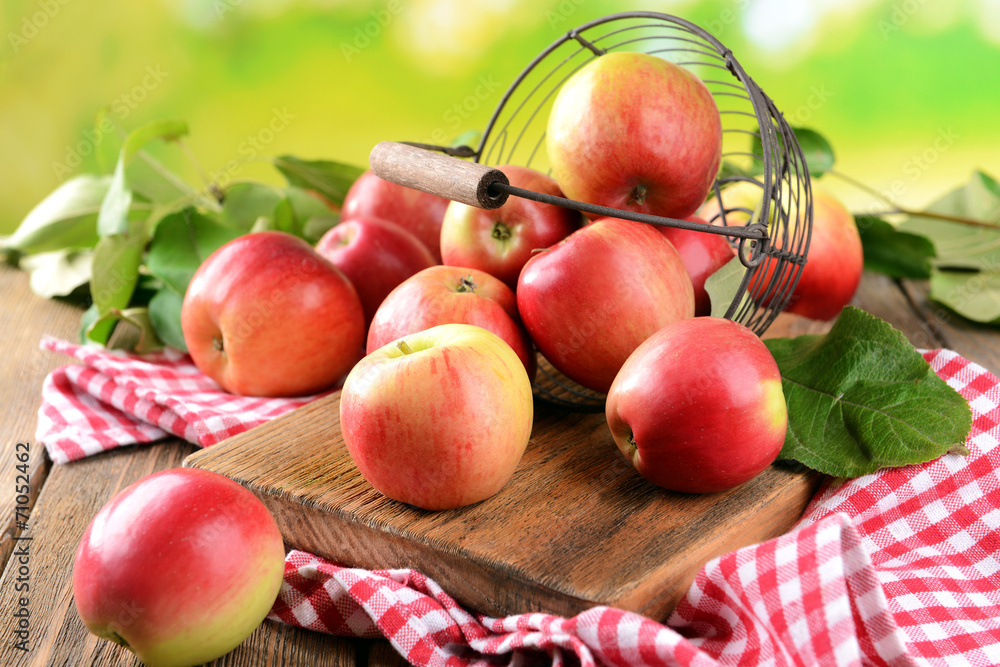 Sweet apples in wicker basket on table on bright background