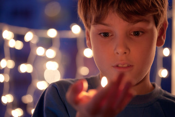 Wall Mural - boy with astonishment looks at a burning candle in a hand