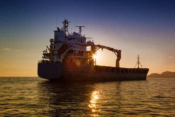 Wall Mural - commercial cargo ship at sunset