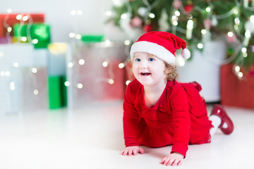 Wall Mural - Laughing happy baby girl in santa hat between Christmas lights