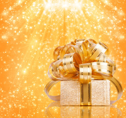 Gift box in gold wrapping paper on a beautiful abstract backgrou