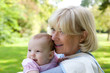 © mimagephotos - Grandmother holding granddaughter outdoors