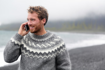 Wall Mural - Smart phone man talking on phone on beach, Iceland