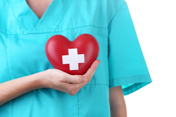 Red heart with cross sign in doctor hand, close-up, isolated