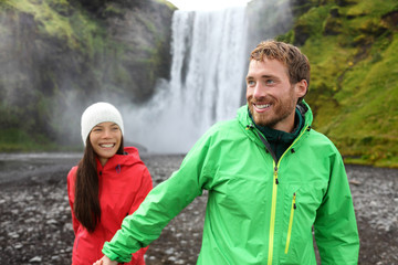 Wall Mural - Happy couple holding hands by waterfall outdoors