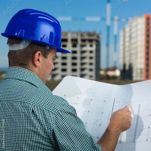 Plakat na papierze fotorealistycznym Inżynier czytający plan budowy