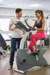 © onoky - Trainer helping a woman with the cycle in a gym
