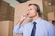 © WavebreakmediaMicro - Businessman using headset in warehouse