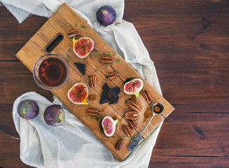 Fresh figs, chocolate and pekan nuts with honey on a wooden boar