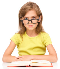 Fototapete - Little girl is reading a book