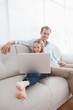 © WavebreakMediaMicro - Casual father and daughter using laptop on the couch