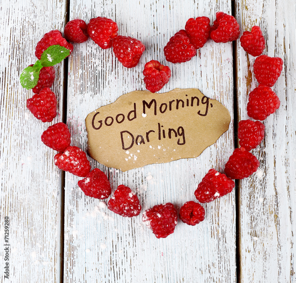 Heart shaped raspberries on wooden background