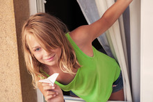 Little Blond Caucasian Girl With Paper Plane In The Window