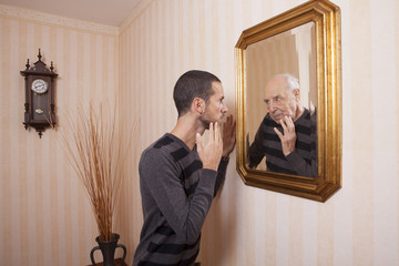 Wall Mural - young man looking at an older himself in the mirror