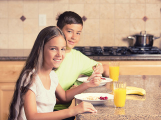 Happy children eating breakfast in a kitchen of their house