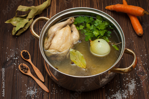 Naklejka na meble chicken broth with vegetables and spices in a saucepan