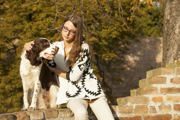 Wall Mural - Happy Young Girl And Dog Sitting On Brick Wall In The Park