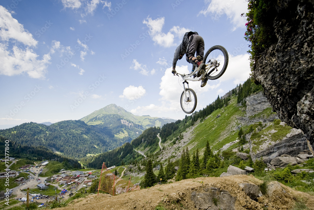 Mountainbiker jumping from a rock - obrazy, fototapety, plakaty 