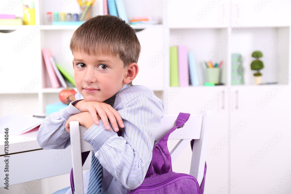 Schoolboy sitting at table in classroom