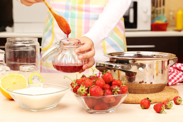 Wall Mural - Woman cooking strawberry jam in kitchen