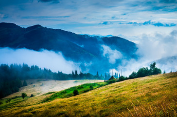 Wall Mural - amazing mountain landscape with fog and a haystack