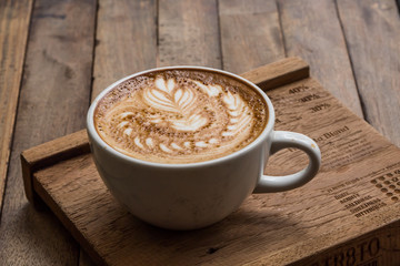 Wall Mural - Cup of hot latte art coffee on wooden table