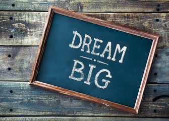 Wall Mural - Hand drawn chalkboard sign DREAM BIG over old wooden table backg
