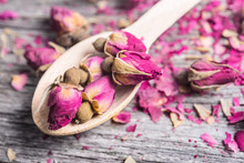 Wooden Spoon With Tea Rose Buds And Petals On Old Wooden Table