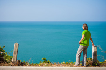 Young man stay on mountain road along tropical island beach and