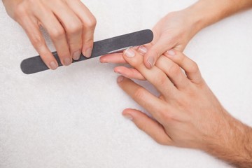 Manicurist filing a customers nails